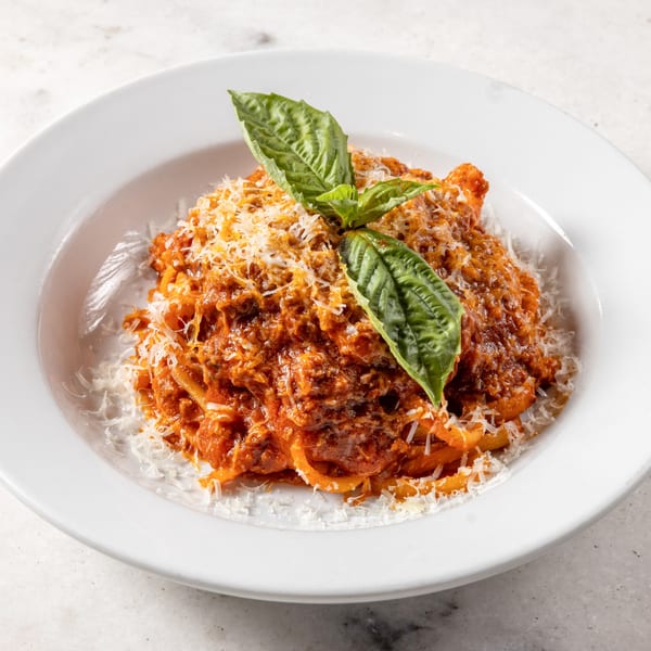 Ribalta's Italian pasta with rich red sauce, grated cheese, and fresh basil in a white bowl.