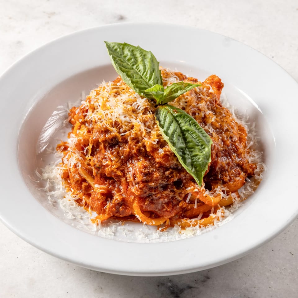 Ribalta's Italian pasta with rich red sauce, grated cheese, and fresh basil in a white bowl.