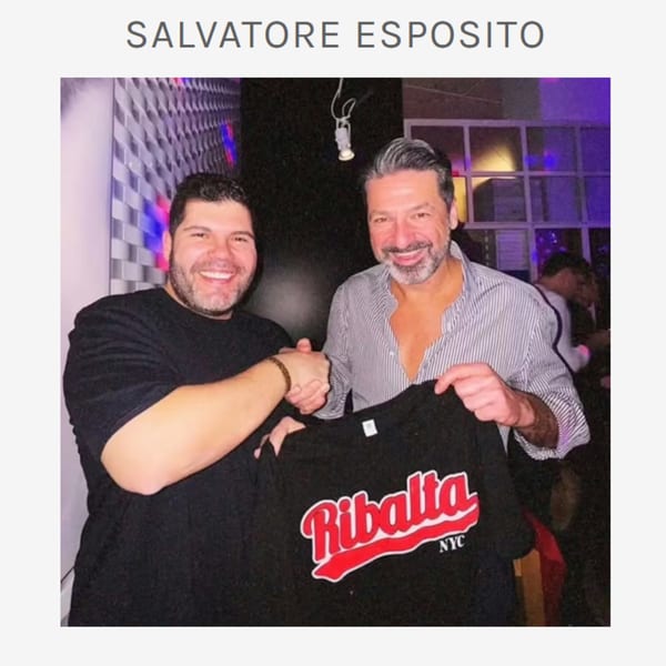 Two men, Salvatore Esposito and another, smiling and shaking hands, holding a black Ribalta NYC t-shirt.