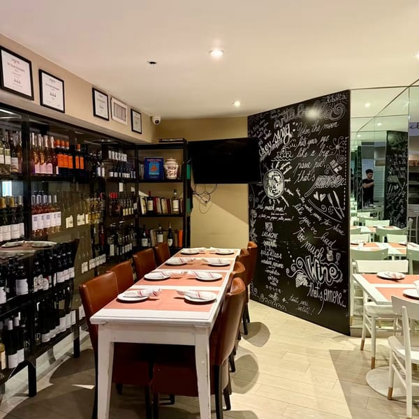 Ribalta's dining room features a long table, wine shelves, and a chalkboard wall with Italian phrases.