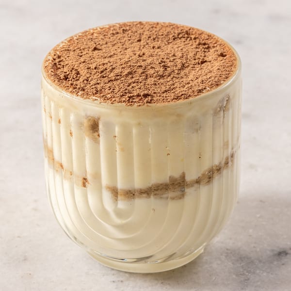 Ribalta's tiramisu dessert in a clear glass, topped with cocoa powder.