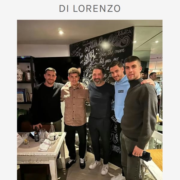 Five men posing together in a casual Italian restaurant setting with a chalkboard wall.