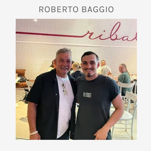 Two men smiling at the camera inside Ribalta, an Italian restaurant, with other diners in the background.