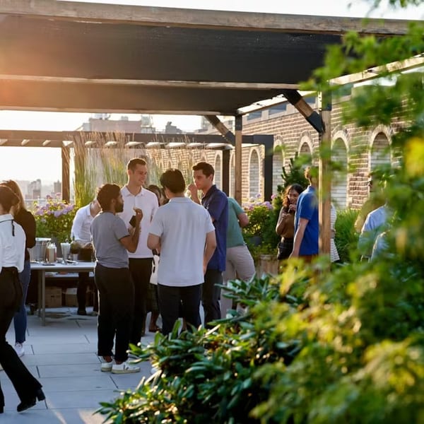 Guests mingle on Ribalta's rooftop patio at sunset, with brick arches and lush greenery.